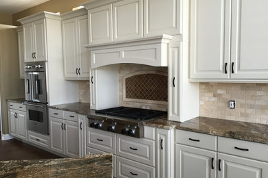 Inredning av ett klassiskt stort linjärt kök och matrum, med en enkel diskho, luckor med upphöjd panel, vita skåp, granitbänkskiva, beige stänkskydd, stänkskydd i metallkakel, rostfria vitvaror, mellanmörkt trägolv och en köksö