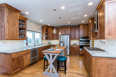 Large transitional u-shaped medium tone wood floor and brown floor enclosed kitchen photo in Phoenix with an undermount sink, shaker cabinets, dark wood cabinets, quartz countertops, gray backsplash, stone tile backsplash, stainless steel appliances and an island