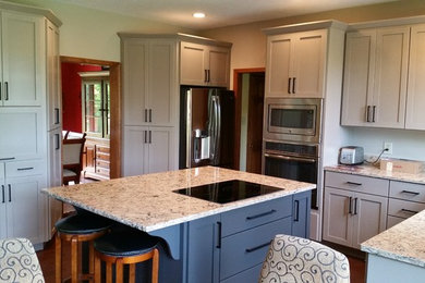 Inspiration for a mid-sized transitional l-shaped dark wood floor eat-in kitchen remodel in Indianapolis with an island, recessed-panel cabinets, gray cabinets, quartz countertops, stainless steel appliances and an undermount sink