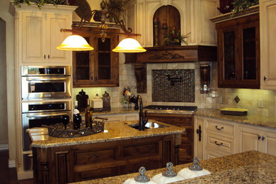 Large arts and crafts u-shaped dark wood floor and brown floor enclosed kitchen photo in Dallas with a double-bowl sink, raised-panel cabinets, beige cabinets, granite countertops, beige backsplash, ceramic backsplash, stainless steel appliances and an island