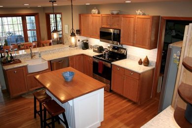 Example of a large classic u-shaped medium tone wood floor kitchen design in Boston with recessed-panel cabinets, medium tone wood cabinets, wood countertops, white backsplash, subway tile backsplash, stainless steel appliances and an island