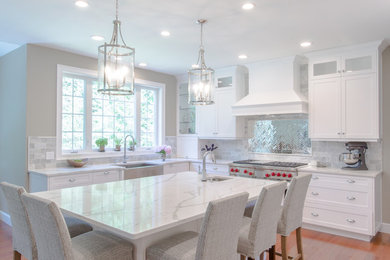 Große Küche mit Landhausspüle, Küchenrückwand in Weiß, Küchengeräten aus Edelstahl, Kücheninsel, braunem Boden und weißer Arbeitsplatte in Boston