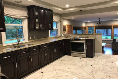 Klassisk inredning av ett avskilt, mellanstort flerfärgad flerfärgat l-kök, med en undermonterad diskho, luckor med upphöjd panel, svarta skåp, granitbänkskiva, grått stänkskydd, stänkskydd i keramik, rostfria vitvaror, marmorgolv och vitt golv