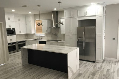 Large minimalist vinyl floor and beige floor open concept kitchen photo in Tampa with a double-bowl sink, shaker cabinets, white cabinets, marble countertops, stainless steel appliances and an island