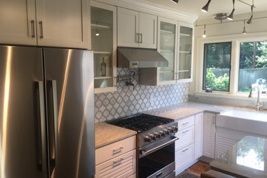Example of a small trendy l-shaped light wood floor eat-in kitchen design in Other with a farmhouse sink, glass-front cabinets, white cabinets, marble countertops, multicolored backsplash, mosaic tile backsplash, stainless steel appliances and a peninsula