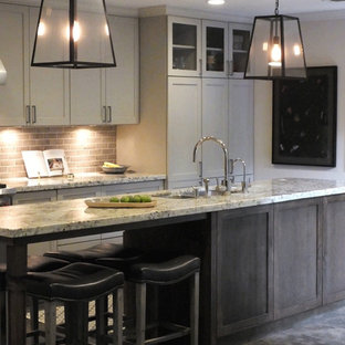 Cette image montre une cuisine américaine parallèle bohème de taille moyenne avec un évier encastré, un placard à porte shaker, des portes de placard en bois sombre, un plan de travail en granite, une crédence beige, une crédence en carrelage métro, un électroménager en acier inoxydable, un sol en calcaire et un îlot central.