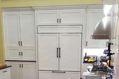 Example of a classic l-shaped open concept kitchen design in Cleveland with white cabinets and an island