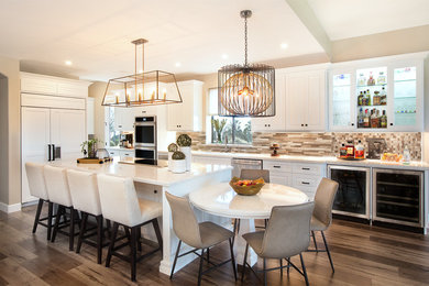 Large transitional l-shaped laminate floor eat-in kitchen photo in Phoenix with an undermount sink, raised-panel cabinets, white cabinets, quartz countertops, multicolored backsplash, mosaic tile backsplash, paneled appliances and an island