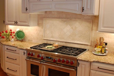 Large elegant u-shaped light wood floor open concept kitchen photo in Nashville with an undermount sink, raised-panel cabinets, white cabinets, granite countertops, beige backsplash, travertine backsplash, paneled appliances and an island