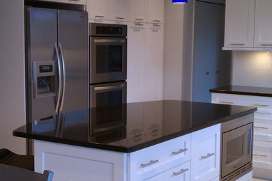 Example of a mid-sized trendy l-shaped eat-in kitchen design in Cleveland with white cabinets, stainless steel appliances, an island, recessed-panel cabinets, granite countertops, white backsplash and ceramic backsplash