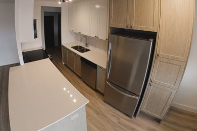 Mid-sized minimalist galley eat-in kitchen photo in Toronto with raised-panel cabinets, light wood cabinets, white backsplash, ceramic backsplash, an island and white countertops