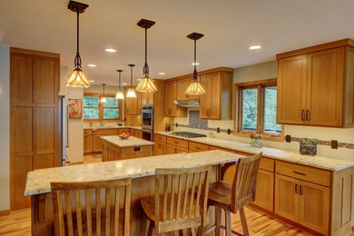 This is an example of a classic kitchen in Minneapolis with flat-panel cabinets, medium wood cabinets, granite worktops, beige splashback, metro tiled splashback, stainless steel appliances, medium hardwood flooring and multiple islands.