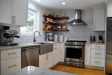 Inspiration for a mid-sized transitional l-shaped light wood floor and yellow floor kitchen remodel in Boston with a farmhouse sink, shaker cabinets, white cabinets, quartz countertops, white backsplash, ceramic backsplash, stainless steel appliances and no island