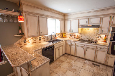 Example of a mid-sized classic u-shaped ceramic tile eat-in kitchen design in Oklahoma City with a drop-in sink, flat-panel cabinets, distressed cabinets, granite countertops, beige backsplash, mosaic tile backsplash, stainless steel appliances and a peninsula