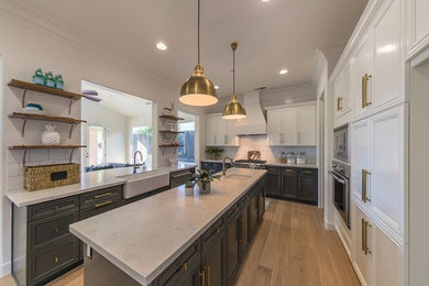 Mid-sized transitional u-shaped light wood floor kitchen pantry photo in Other with a farmhouse sink, raised-panel cabinets, gray cabinets, quartz countertops, white backsplash, subway tile backsplash, stainless steel appliances and an island