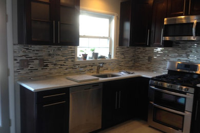 This is an example of a large traditional u-shaped kitchen/diner in Wilmington with a submerged sink, recessed-panel cabinets, dark wood cabinets, engineered stone countertops, white splashback, mosaic tiled splashback, stainless steel appliances, ceramic flooring, no island and beige floors.