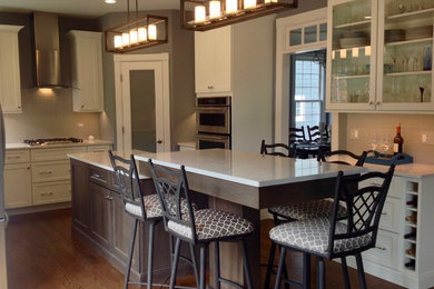 Example of a mid-sized trendy u-shaped medium tone wood floor and brown floor eat-in kitchen design in Chicago with an undermount sink, shaker cabinets, white cabinets, quartz countertops, gray backsplash, subway tile backsplash, stainless steel appliances and an island