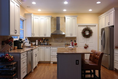 Mid-sized elegant l-shaped light wood floor and brown floor eat-in kitchen photo in Baltimore with an undermount sink, recessed-panel cabinets, white cabinets, granite countertops, beige backsplash, ceramic backsplash, stainless steel appliances and an island