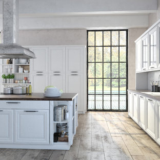 Cette photo montre une cuisine chic fermée avec un évier 2 bacs, un placard avec porte à panneau surélevé, des portes de placard blanches, un plan de travail en bois, une crédence blanche, une crédence en bois, un sol en contreplaqué, un îlot central, un sol beige et un plan de travail marron.