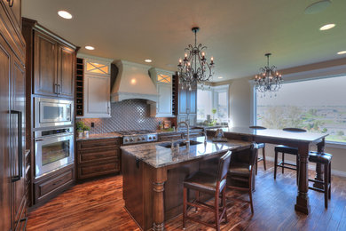 Eat-in kitchen - large transitional l-shaped medium tone wood floor eat-in kitchen idea in Seattle with an undermount sink, medium tone wood cabinets, granite countertops, brown backsplash, stainless steel appliances and an island