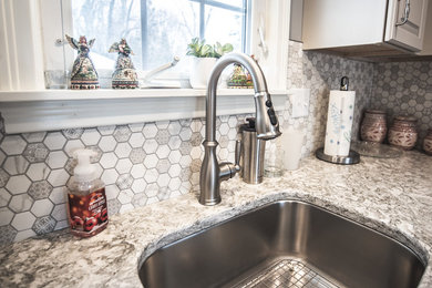 Inspiration for a mid-sized timeless l-shaped eat-in kitchen remodel in New York with a single-bowl sink, raised-panel cabinets, gray cabinets, quartz countertops, multicolored backsplash, glass tile backsplash, stainless steel appliances, an island and gray countertops