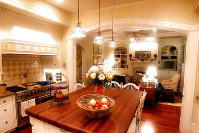 ローリーにあるトラディショナルスタイルのおしゃれなキッチン (白いキャビネット、ベージュキッチンパネル、シルバーの調理設備) の写真