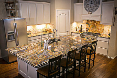 Example of a large transitional l-shaped dark wood floor eat-in kitchen design in Houston with an undermount sink, recessed-panel cabinets, white cabinets, granite countertops, beige backsplash, stone tile backsplash, stainless steel appliances and an island