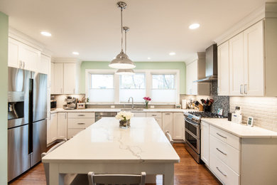 Kitchen - mid-sized transitional u-shaped medium tone wood floor and brown floor kitchen idea in DC Metro with an undermount sink, shaker cabinets, white cabinets, quartz countertops, gray backsplash, stainless steel appliances, an island and white countertops