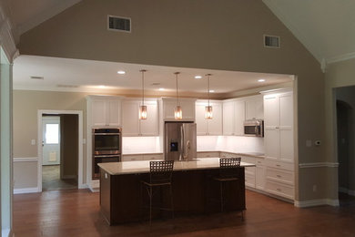 Inspiration for a large transitional l-shaped medium tone wood floor and brown floor open concept kitchen remodel in Dallas with shaker cabinets, white cabinets, granite countertops, stainless steel appliances, an island, a farmhouse sink, white backsplash and subway tile backsplash