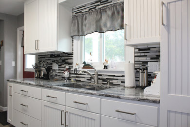グランドラピッズにあるおしゃれなII型キッチン (白いキャビネット、珪岩カウンター、メタリックのキッチンパネル、シルバーの調理設備、クッションフロア、グレーの床) の写真