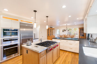 Photo of a large modern u-shaped kitchen/diner in San Francisco with a submerged sink, shaker cabinets, white cabinets, composite countertops, beige splashback, glass tiled splashback, stainless steel appliances, medium hardwood flooring and an island.