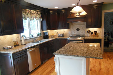 This is an example of a medium sized traditional kitchen in New York with a submerged sink, raised-panel cabinets, dark wood cabinets, granite worktops, beige splashback, stainless steel appliances, medium hardwood flooring and an island.