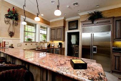 Inredning av ett medelhavsstil mellanstort kök, med en dubbel diskho, luckor med upphöjd panel, skåp i mörkt trä, granitbänkskiva, beige stänkskydd, stänkskydd i keramik, rostfria vitvaror och klinkergolv i keramik