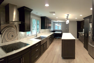 Eat-in kitchen - large modern galley light wood floor eat-in kitchen idea in Boston with a farmhouse sink, marble countertops, ceramic backsplash, stainless steel appliances, shaker cabinets, black cabinets, gray backsplash and an island