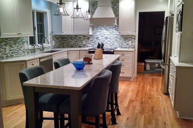 Example of a mid-sized transitional u-shaped medium tone wood floor open concept kitchen design in New York with a single-bowl sink, shaker cabinets, white cabinets, quartz countertops, blue backsplash, stainless steel appliances and an island