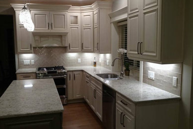 Inspiration for a mid-sized transitional l-shaped medium tone wood floor and brown floor eat-in kitchen remodel in Other with a double-bowl sink, raised-panel cabinets, white cabinets, marble countertops, beige backsplash, glass tile backsplash, stainless steel appliances and an island