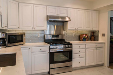 Example of a mid-sized classic u-shaped ceramic tile and white floor eat-in kitchen design in Los Angeles with an undermount sink, raised-panel cabinets, white cabinets, gray backsplash, subway tile backsplash, stainless steel appliances and white countertops