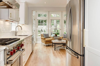 Inspiration for a transitional light wood floor kitchen remodel in DC Metro with shaker cabinets, white cabinets, quartz countertops, white backsplash, ceramic backsplash, stainless steel appliances and white countertops