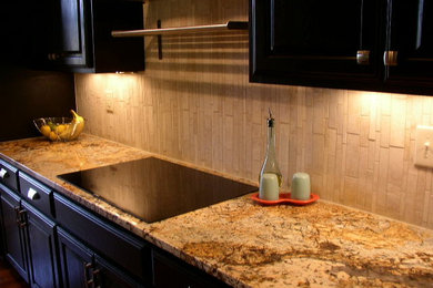 Example of a large trendy u-shaped eat-in kitchen design in Austin with raised-panel cabinets, black cabinets, granite countertops, beige backsplash, mosaic tile backsplash, stainless steel appliances and an island
