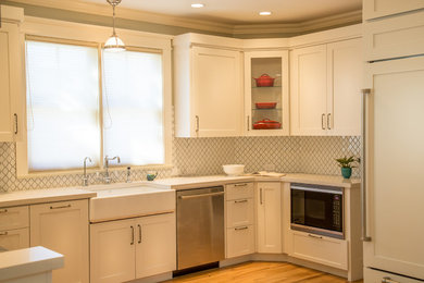 Eat-in kitchen - mid-sized traditional u-shaped light wood floor eat-in kitchen idea in Denver with a farmhouse sink, shaker cabinets, white cabinets, white backsplash, solid surface countertops, mosaic tile backsplash, paneled appliances and a peninsula