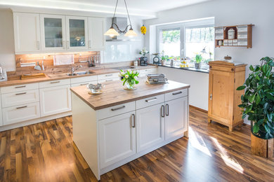 Kitchen - mid-sized traditional l-shaped laminate floor and multicolored floor kitchen idea in Boston with an undermount sink, flat-panel cabinets, white cabinets, laminate countertops, brown backsplash, stainless steel appliances, an island and multicolored countertops