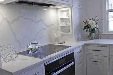 Photo of a medium sized traditional kitchen/diner in Boston with a submerged sink, recessed-panel cabinets, white cabinets, white splashback, stone slab splashback, integrated appliances, medium hardwood flooring and an island.