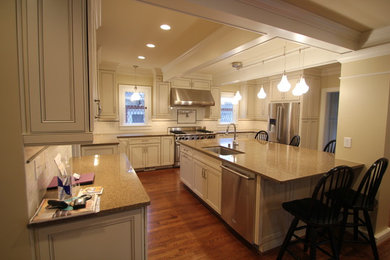 Immagine di un cucina con isola centrale tradizionale con top in granito, paraspruzzi bianco, elettrodomestici in acciaio inossidabile e pavimento in legno massello medio
