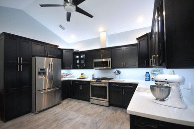 Enclosed kitchen - large contemporary u-shaped porcelain tile enclosed kitchen idea in Orlando with an undermount sink, recessed-panel cabinets, black cabinets, quartzite countertops and stainless steel appliances