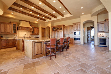 Inspiration for a timeless kitchen remodel in Phoenix with raised-panel cabinets, medium tone wood cabinets, granite countertops, beige backsplash, stone tile backsplash, stainless steel appliances and two islands