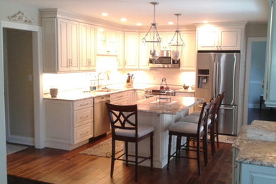 Inspiration for a mid-sized timeless u-shaped medium tone wood floor and brown floor enclosed kitchen remodel in Philadelphia with raised-panel cabinets, white cabinets, granite countertops, an island, gray countertops, an undermount sink, white backsplash, subway tile backsplash and stainless steel appliances