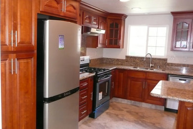 Example of a large galley ceramic tile enclosed kitchen design in Los Angeles with a drop-in sink, raised-panel cabinets, medium tone wood cabinets, granite countertops, stainless steel appliances and no island
