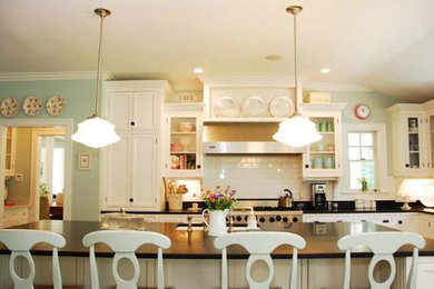 Inspiration for a large country u-shaped dark wood floor eat-in kitchen remodel in Portland Maine with a farmhouse sink, recessed-panel cabinets, white cabinets, white backsplash, ceramic backsplash, stainless steel appliances and an island