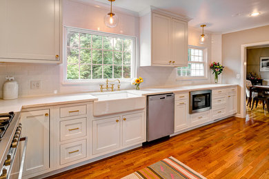 Inspiration for a mid-sized farmhouse l-shaped medium tone wood floor enclosed kitchen remodel in Columbus with a farmhouse sink, shaker cabinets, white cabinets, marble countertops, white backsplash, subway tile backsplash, stainless steel appliances and no island