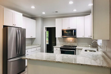 Inspiration for a mid-sized timeless u-shaped porcelain tile and brown floor eat-in kitchen remodel in Richmond with an undermount sink, recessed-panel cabinets, white cabinets, granite countertops, white backsplash, stone slab backsplash, stainless steel appliances, a peninsula and white countertops